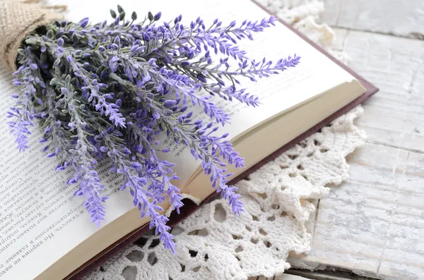 Bunch of lavender laying upon open book on vintage crocheted doi