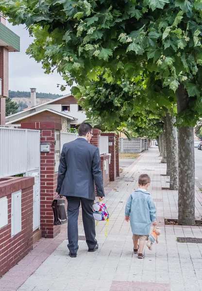 Father and little son walking on the street to the school