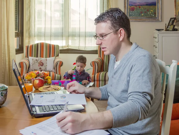 Father working in home office and son playing