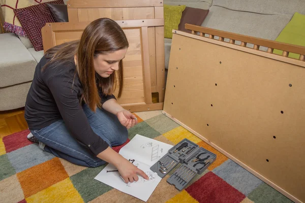 Girl reading instructions to assemble furniture