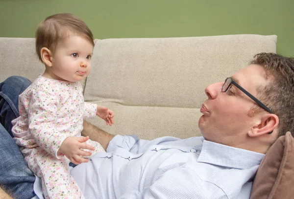 Happy father playing with cute baby in a sofa