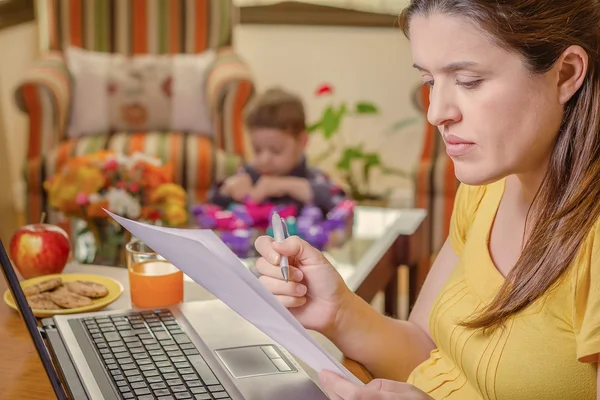 Pregnant mother working in home office with son