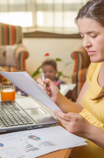 Pregnant mother working in home office with son