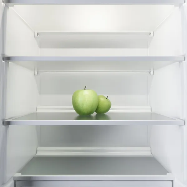 Two apples in open empty refrigerator