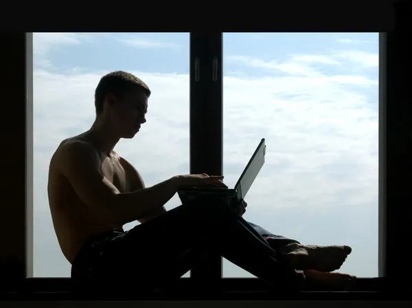 Silhouetted Man Working on a Laptop