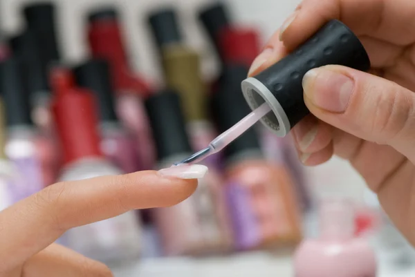 Woman applying pink nail polish