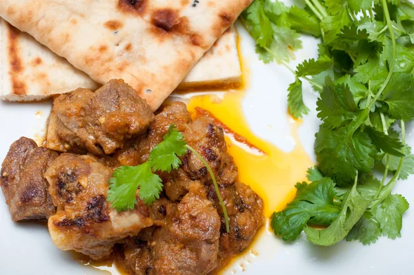 Lamb curry coriander and Naan close up on a white plate