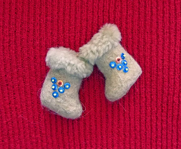 Cute felt boots with sequins on red sweater close-up
