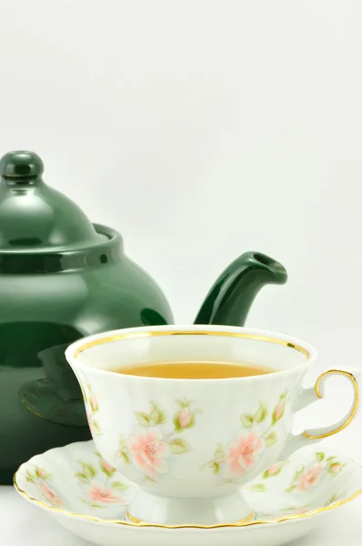 A cup of tea and green teapot on a white background