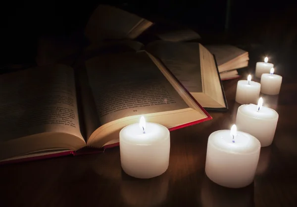 Open books and candles on dark wood table