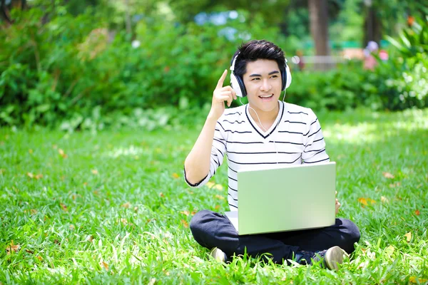 Young handsome Asian student with computer in outdoor