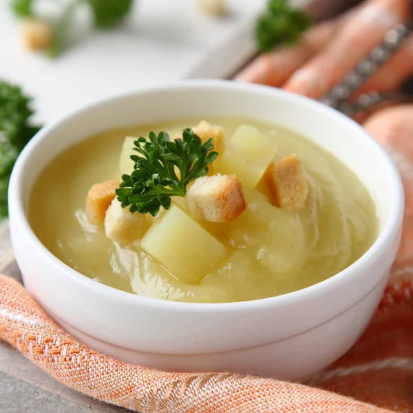 Creamy sweet potato soup with croutons and parsley in white bowl