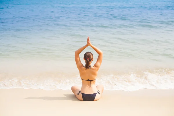 Caucasian woman practicing yoga on beach