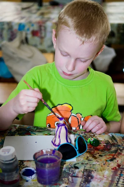 Boy painting russian toy
