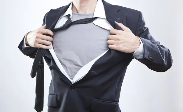 Young businessman acting like a super hero and tearing his shirt off