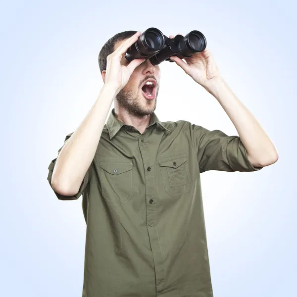 Young man looking through binoculars, surprise face expression
