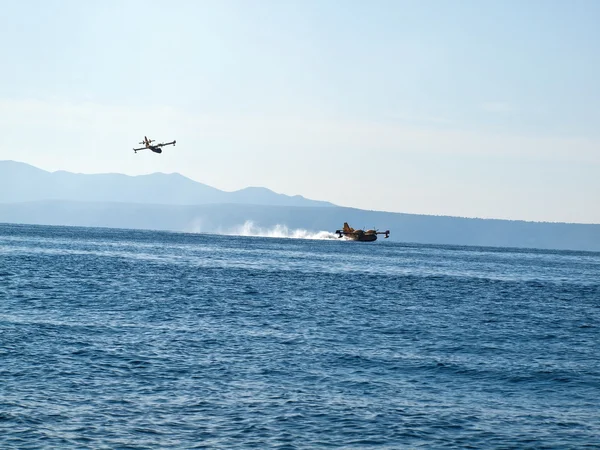 Two fire fighter airplanes landing at sea