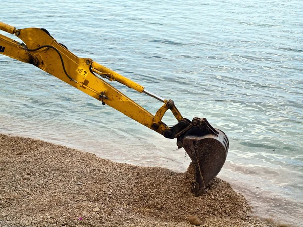 Excavator digging near the sea