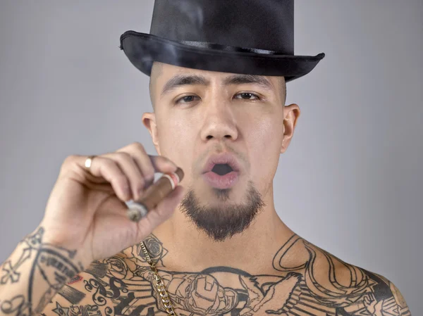 Man with body tattoo smoking cigar