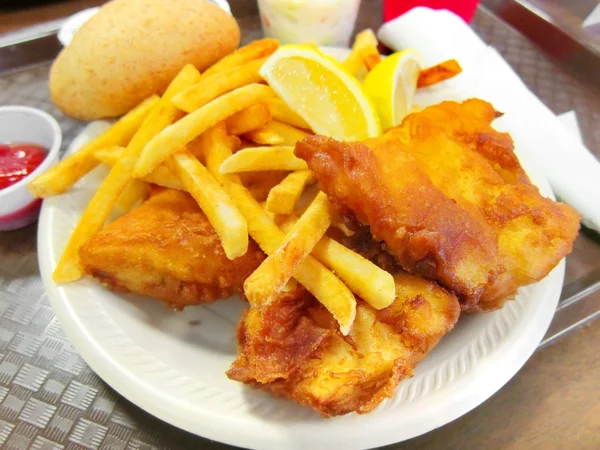 Delicious battered breaded fish on a plate with french fries, coleslaw salad and ketchup fish fry