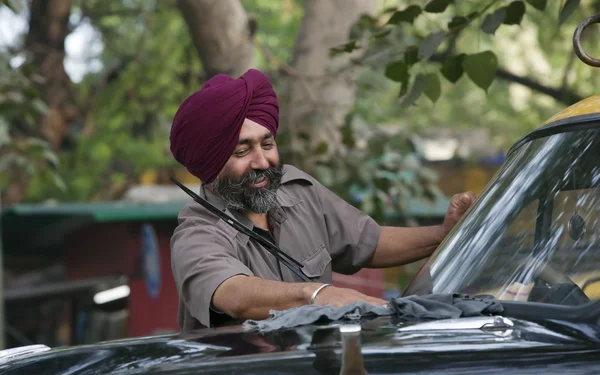 Sikh taxi driver standing next to his vehicle