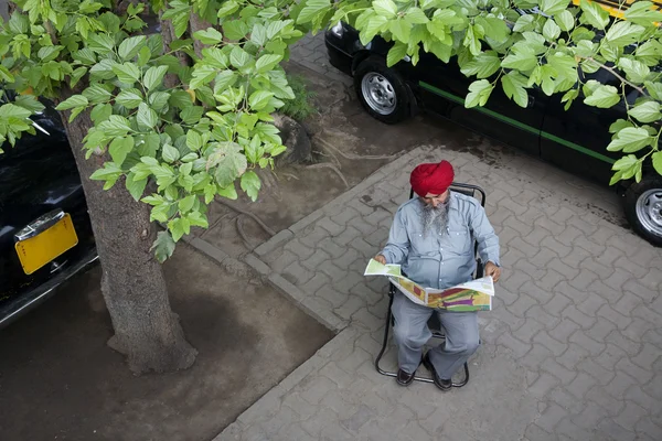 Sikh taxi driver reading the newspaper