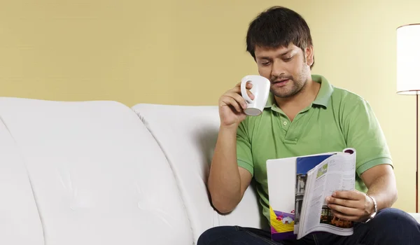 Man reading a magazine while drinking coffee