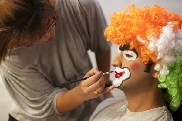 Make up artist applying make up to clown