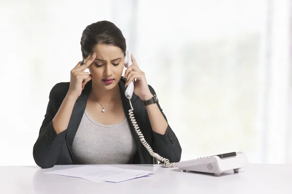 Tensed businesswoman answering telephone