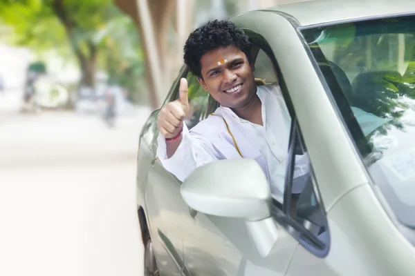 South Indian man gesturing thumbs up in new car
