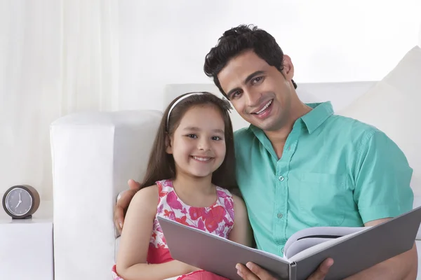 Happy father and daughter reading story book