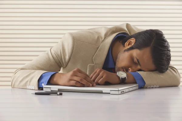 Young businessman sleeping on laptop