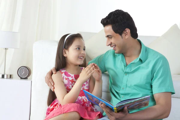 Happy father and daughter reading story book