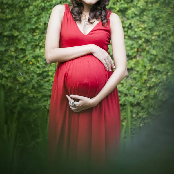 Image of pregnant woman touching her belly with hands relaxing o
