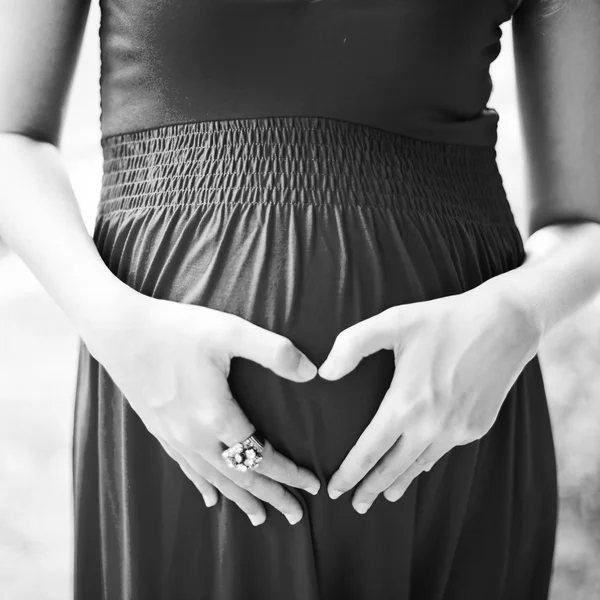 Image of pregnant woman touching her belly with depicting heart