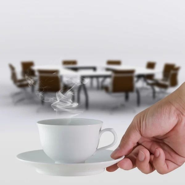 Coffee cup in hand business and meeting room background