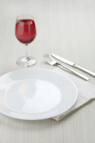 Place setting with white plates and red wine