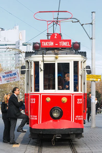Red classic tram with passengers entering at the Taksim