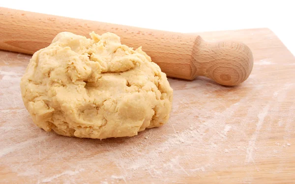 Wooden rolling pin and a fresh ball of pastry on a floured board