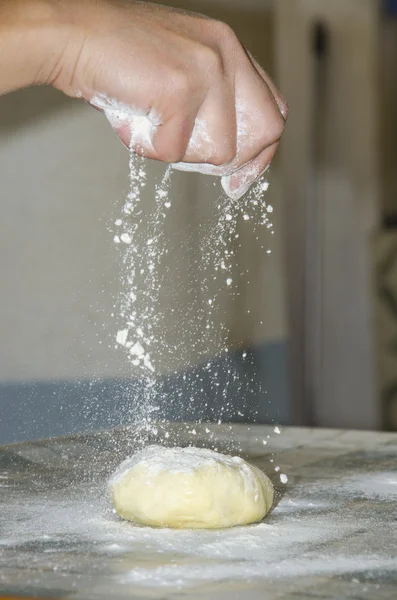 Woman makes and prepares pastry in a bakery kitchen. Adding flour bits