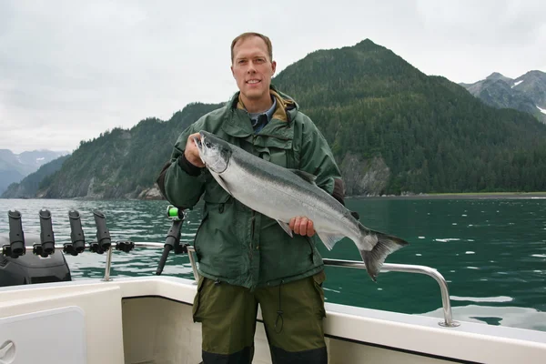 Happy fisherman in holds big silver salmon