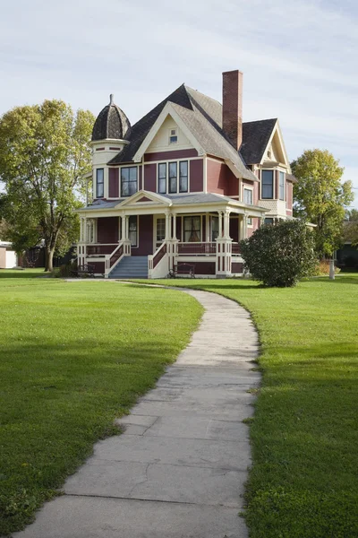 Victorian house with lawn and sidewalk on sunny afternoon