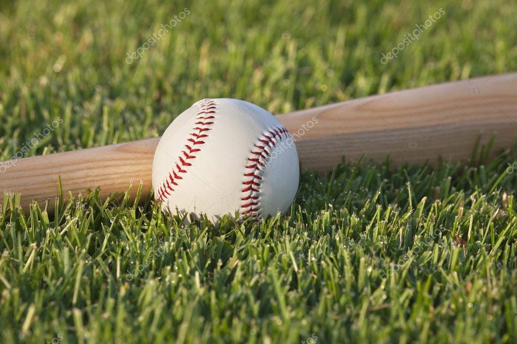 Baseball and bat on grass field in the morning sunlight — Stock Photo