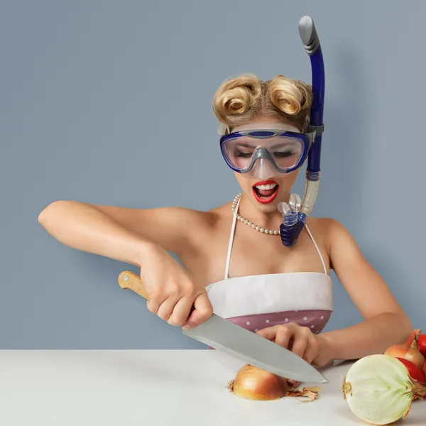 Young woman cutting onion in diving mask