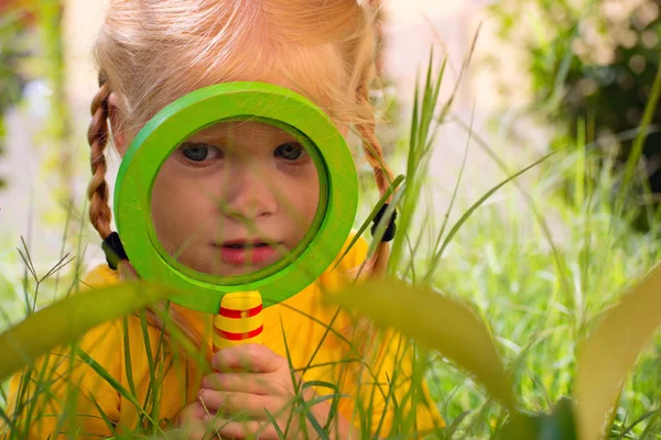 Girl with surprise looks through a magnifying glass