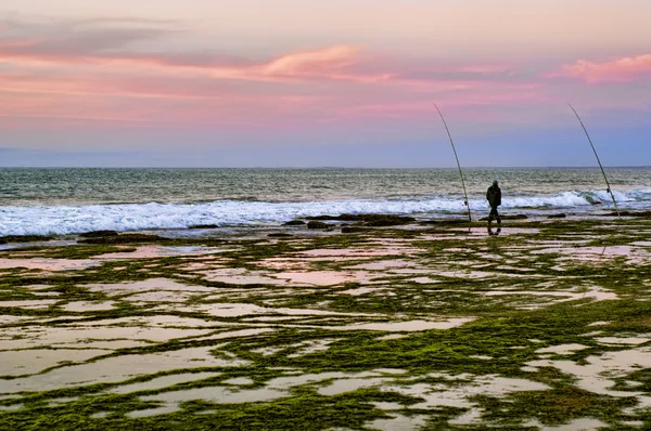 Fisherman with fishing rod on the beach
