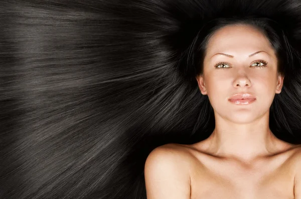 Close-up portrait of a beautiful young woman with elegant black long shiny hair, conceptual hairstyle