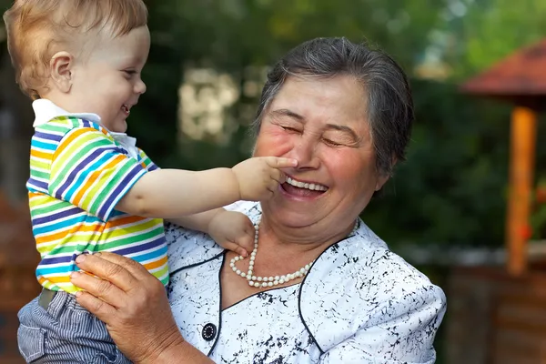 Cute grandson grabbing the nose of laughing great grandmother. f