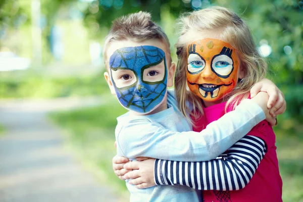 Two face painted little friends embracing outside