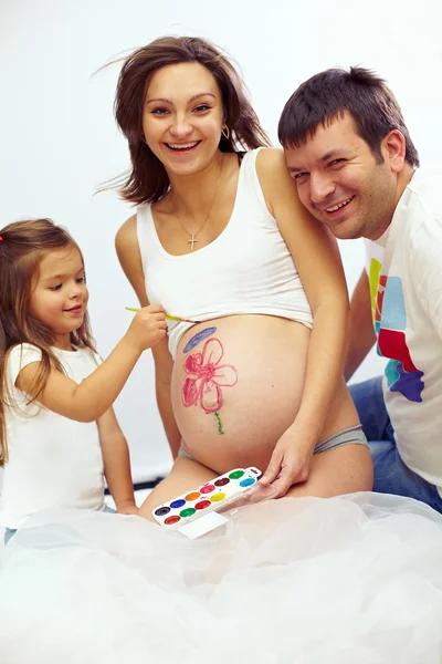 Beautiful happy pregnant family of tree are drawing mom